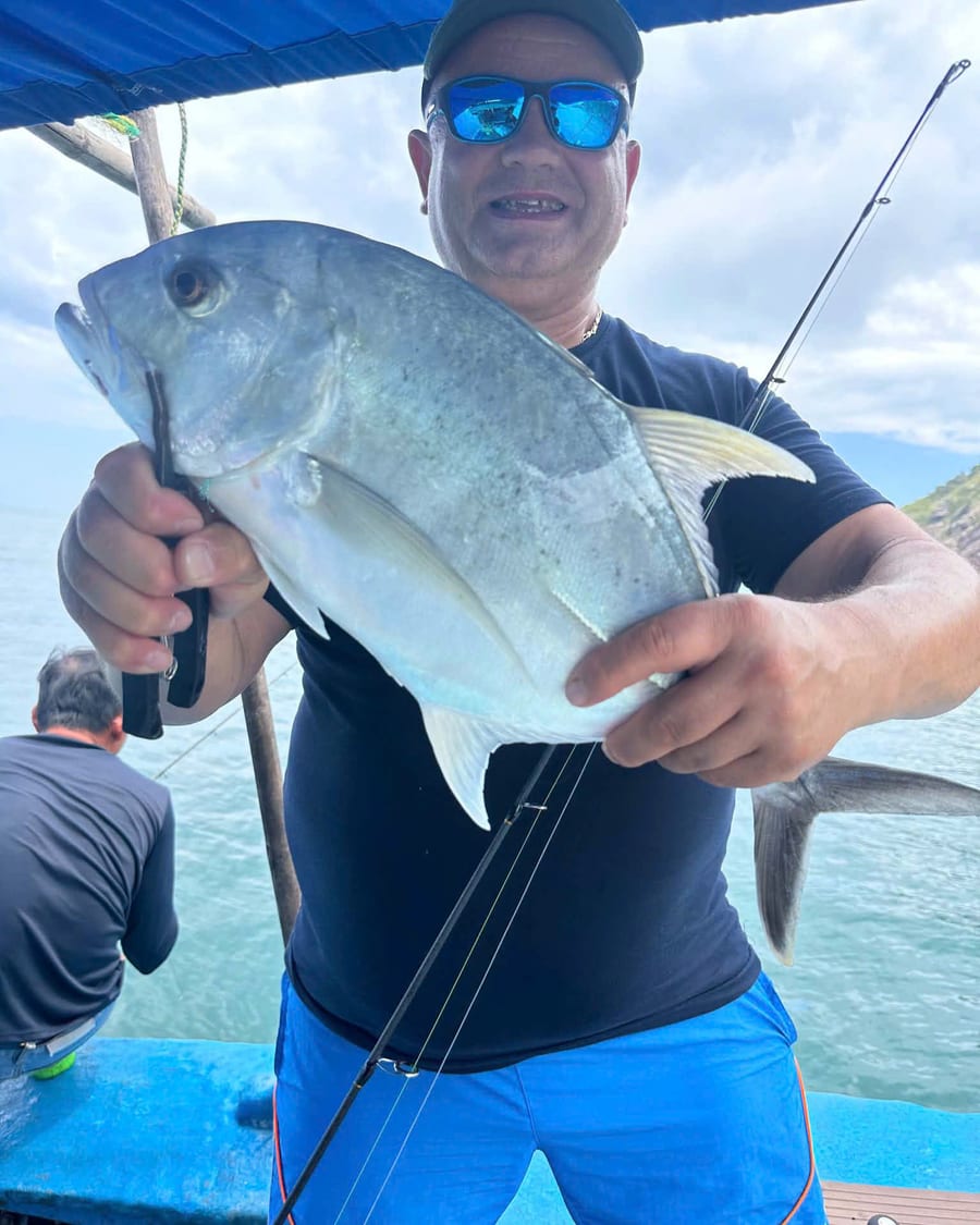 Angler holding a giant trevally with the rod still in hand