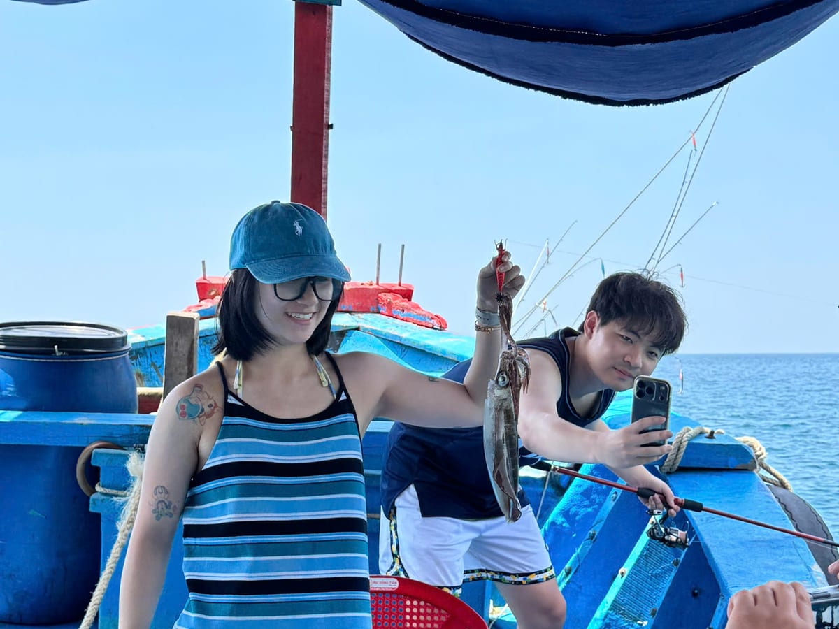 Two guests fishing under the boat canopy on an inshore day trip in Nha Trang